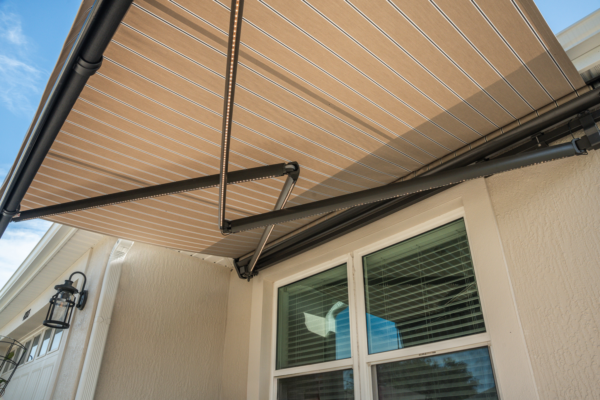 Retractable awning with bronze housing and putty regimental fabric